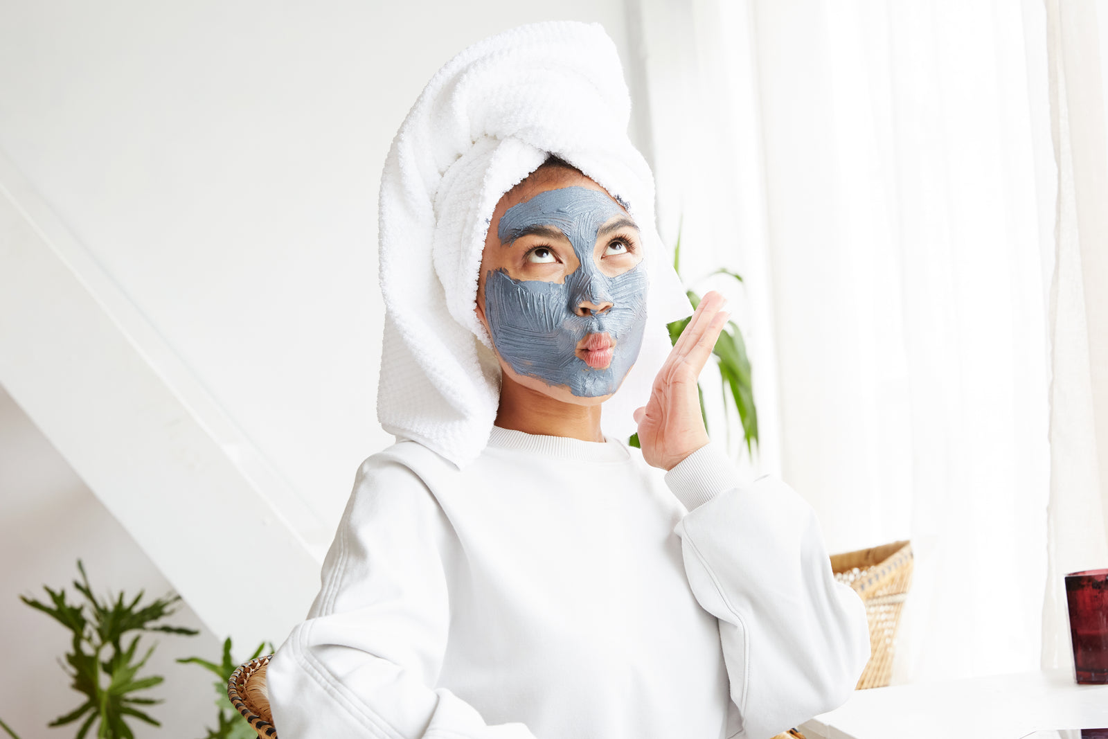 Woman mid-skincare-routine, smiling at herself in the mirror